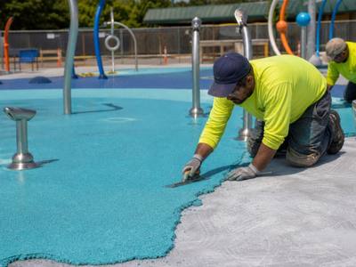 Blue rubber surfacing going down on a splash pad